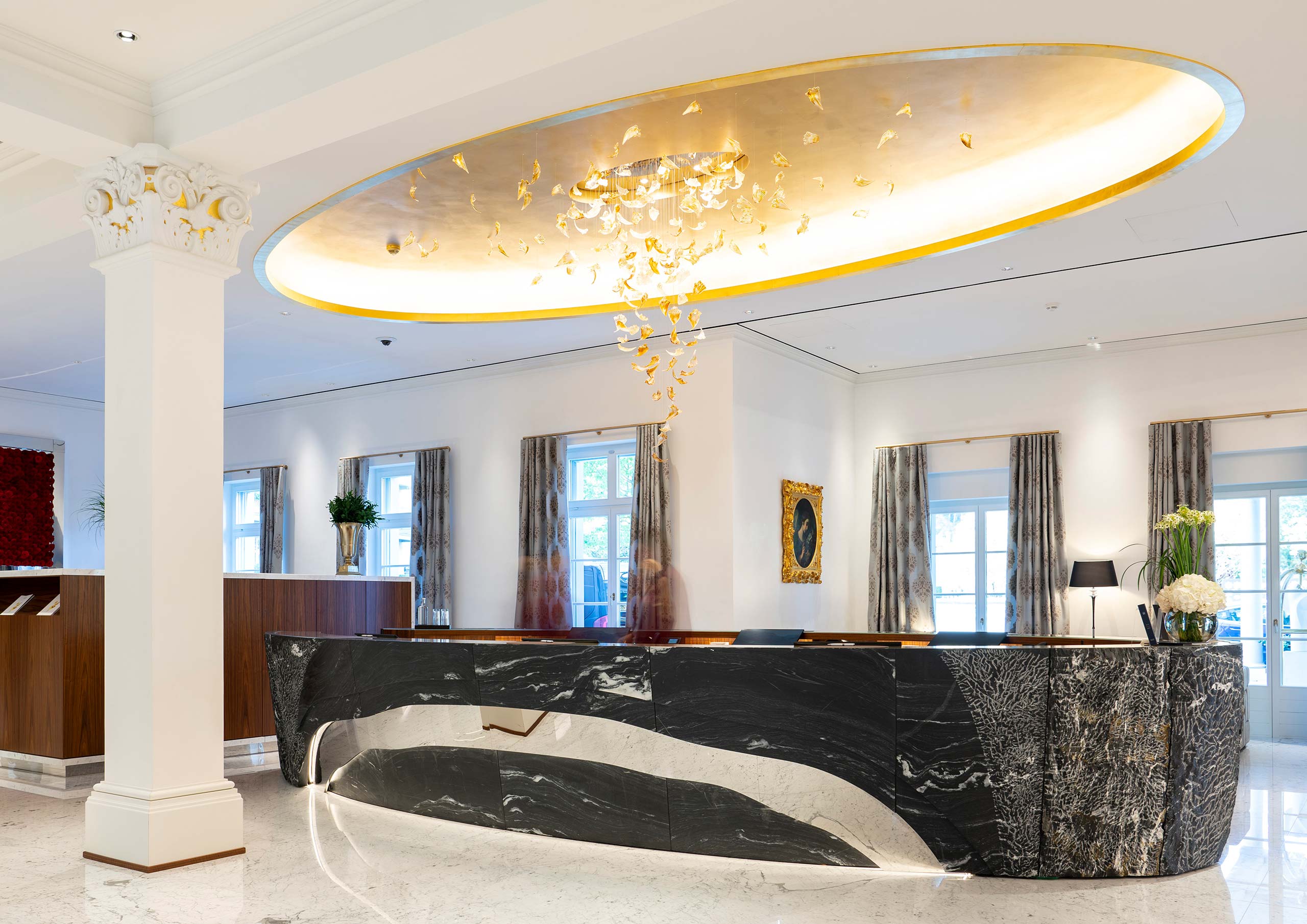 Elegante Eingangshalle mit individuell gefertigtem Empfangstresen aus Naturstein von F/LIST im Hotel Quellenhof.