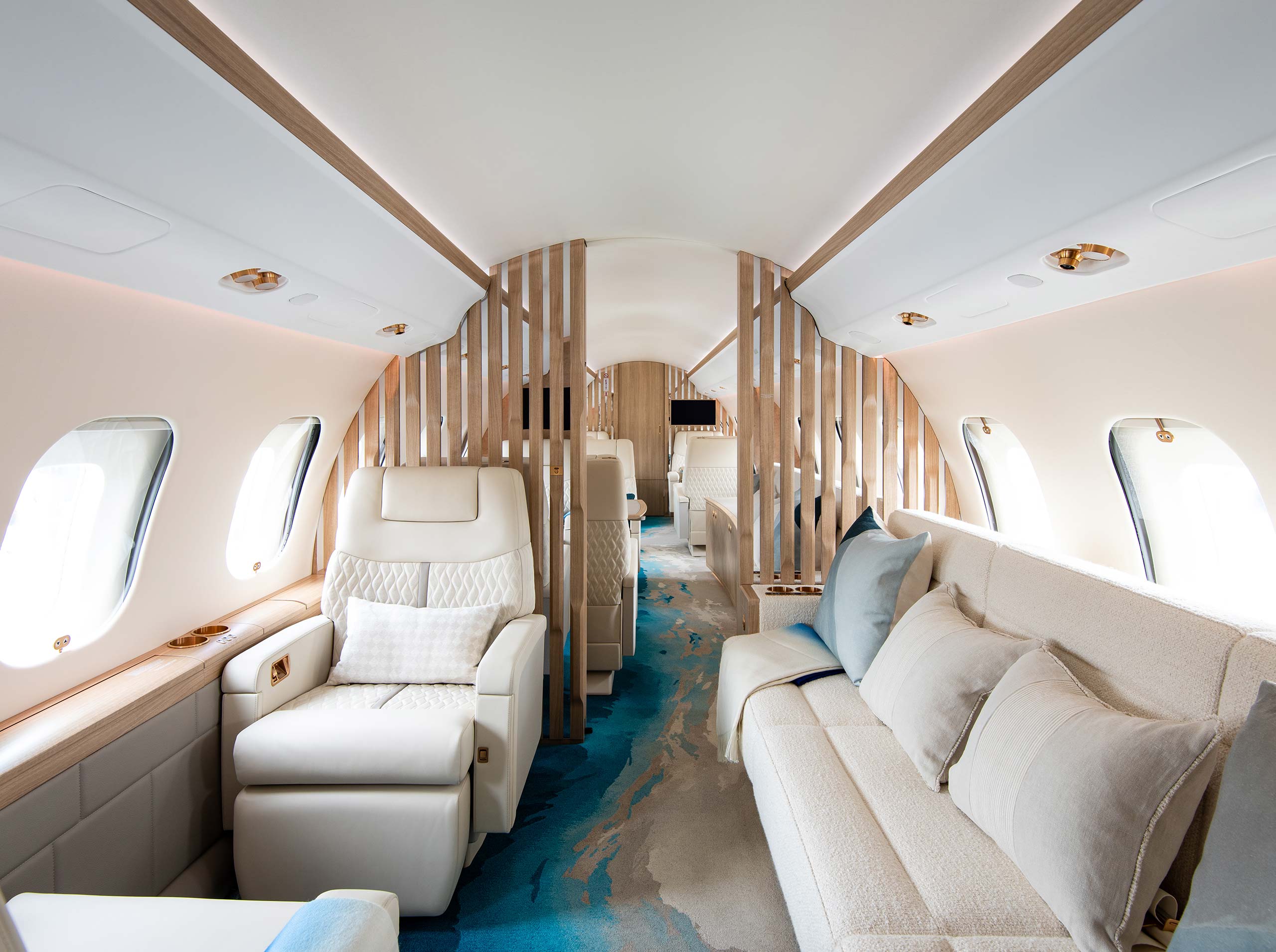 Gesamtkabine einer Global 6000 mit hellem Sofa, Liegesitz und raumgliedernden Holzlamellen