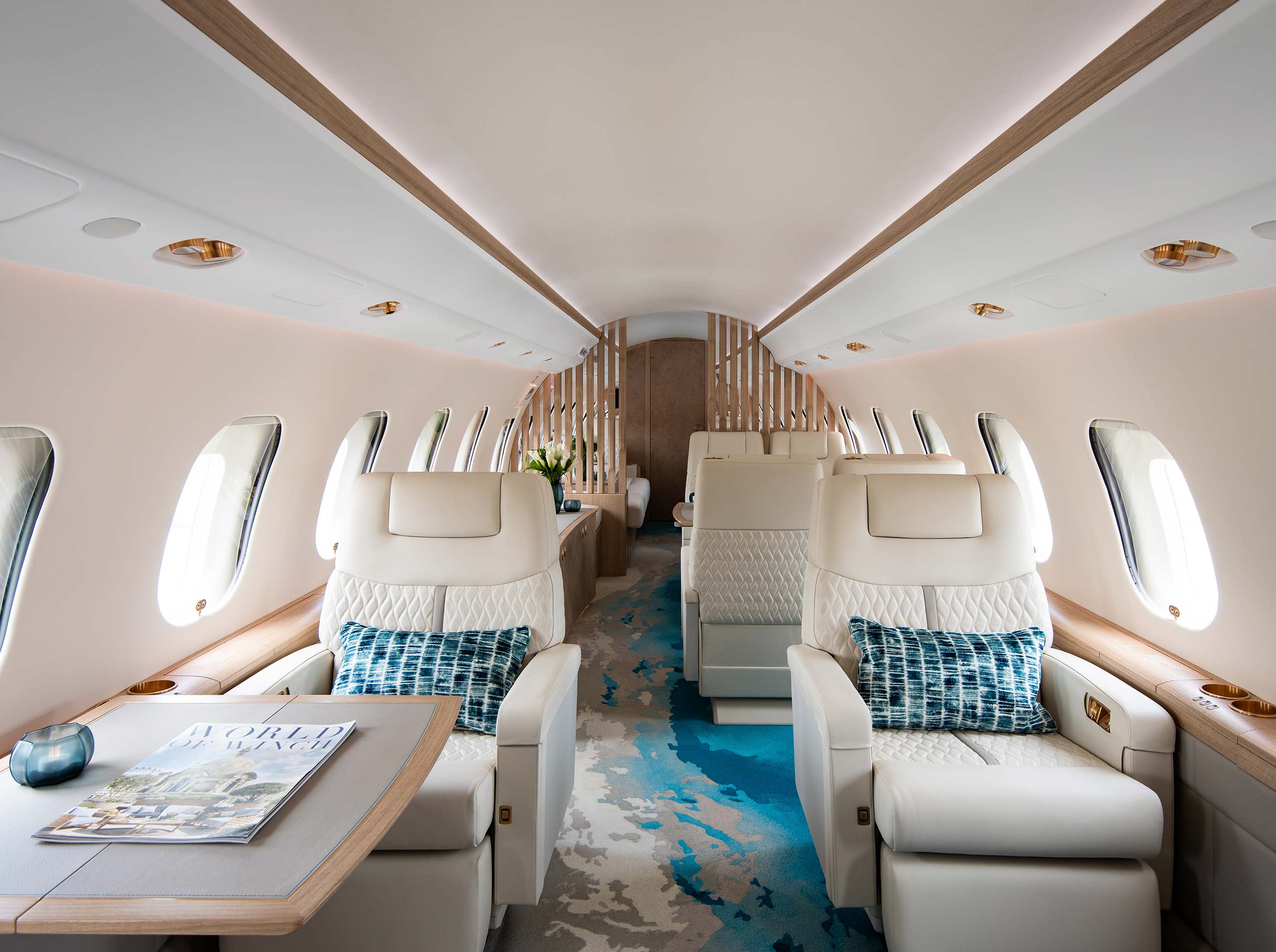 Luxuriös ausgestattete Kabine einer Global 6000 mit hellen Ledersitzen, strukturiertem Teppich in Blau- und Sandtönen sowie natürlichen Holzelementen