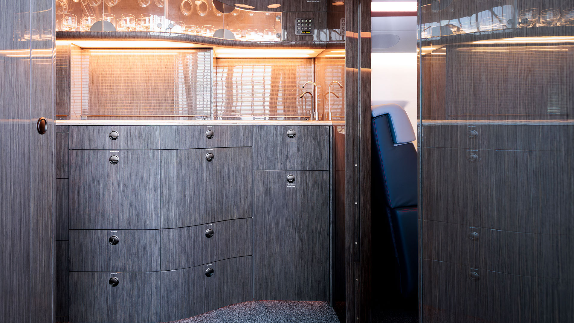 Detailansicht der Galley mit gebürsteten Holzoberflächen, Metallgriffen und eingelassenem Spülbecken