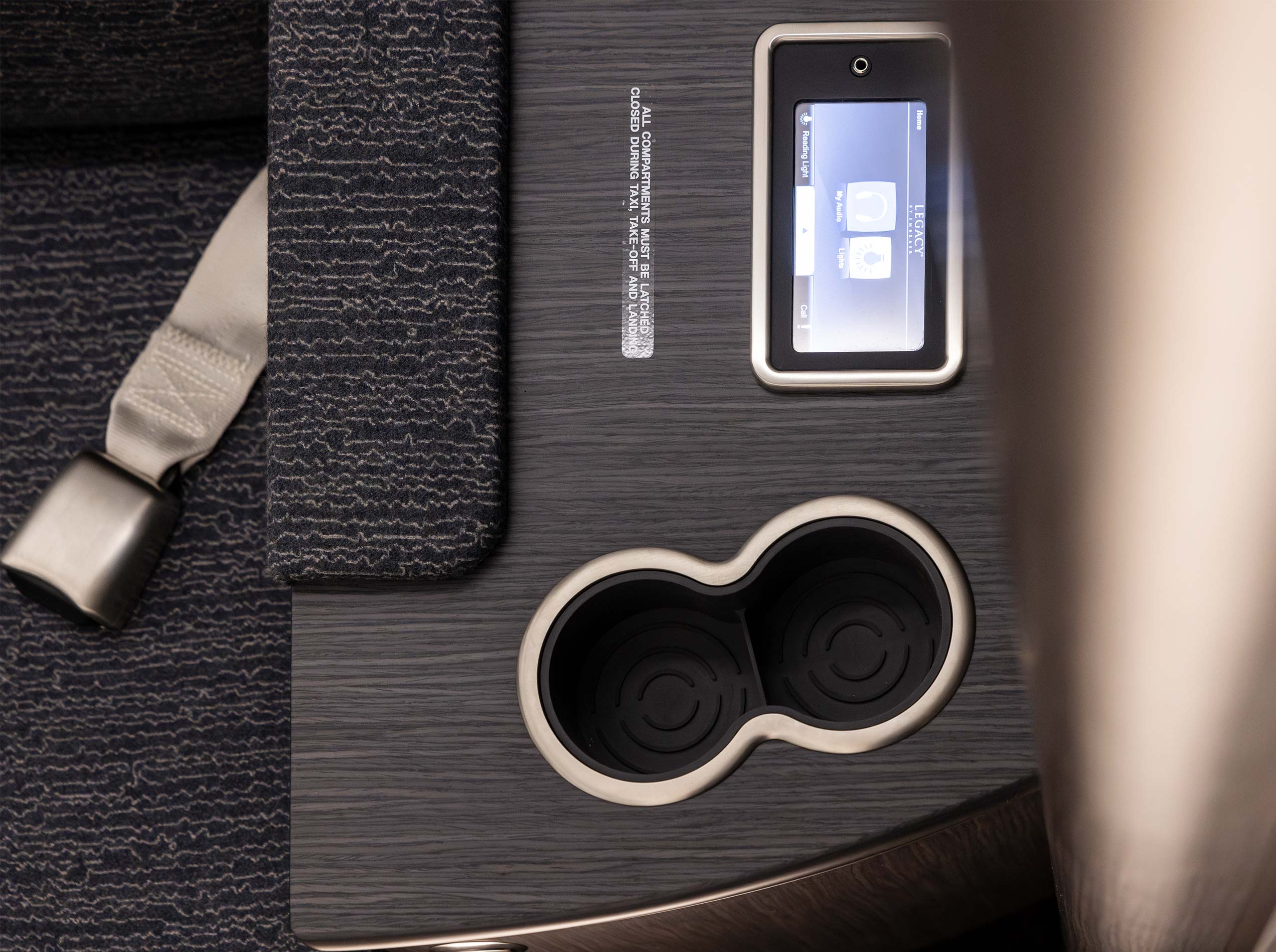 Nahaufnahme eines Sideledge-Bereichs mit Touchpanel, Getränkehalter und strukturiertem Furnier